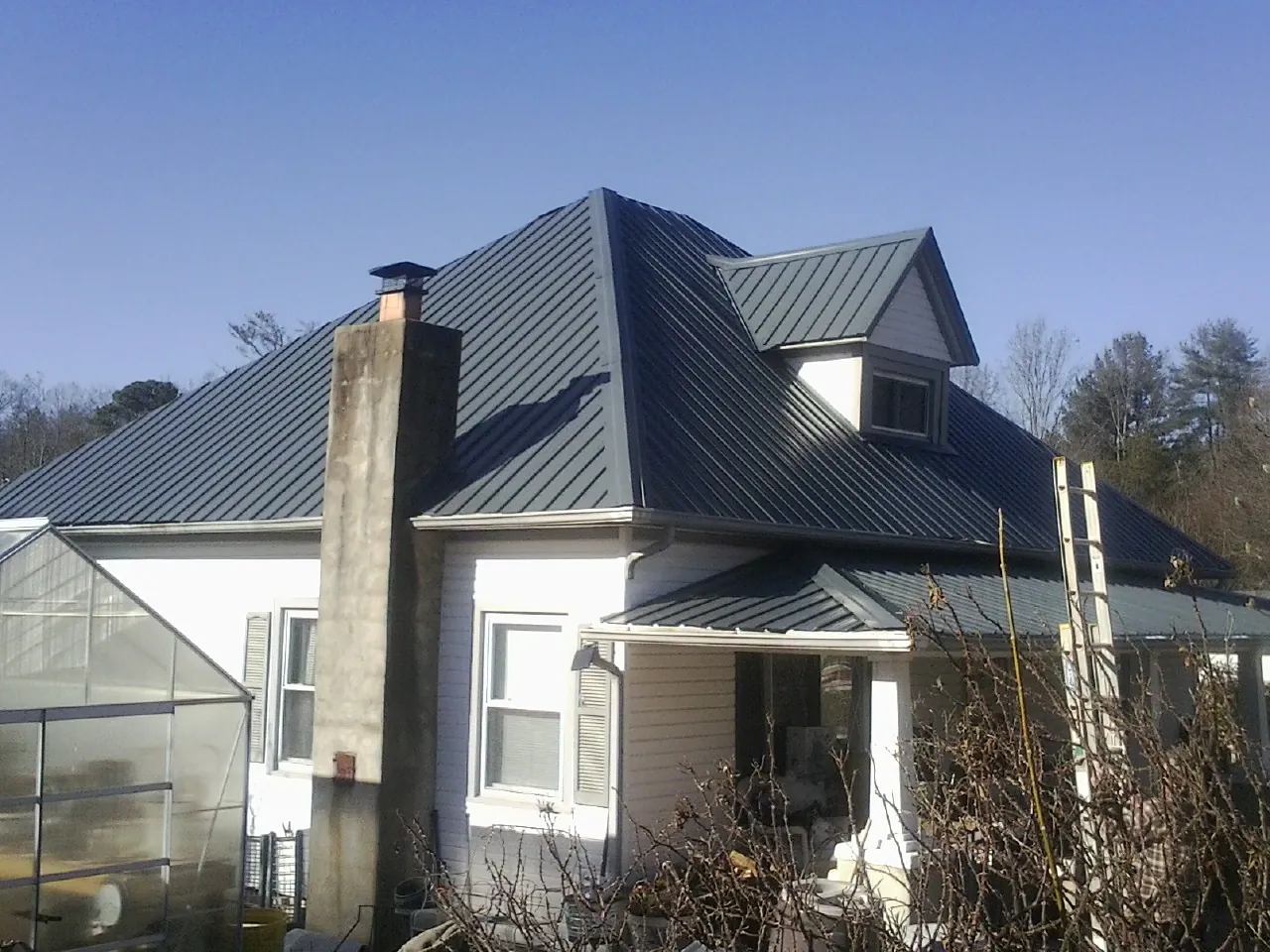 Dark blue standing seam metal roof on a white farmhouse with dormer — Slate & Tile Roof Repair by Roofing Brothers in Creve Coeur