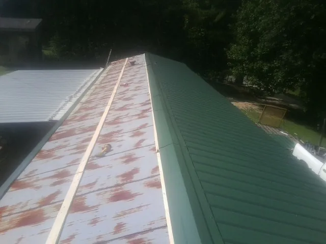 Old rusted panels beside newly installed green metal roofing — Wind Damage Roof Repair by Roofing Brothers in Creve Coeur