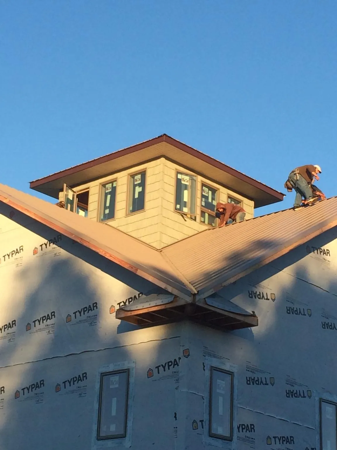 Roofers working around a rooftop cupola on a new metal roof at sunset — Roof Waterproofing in Creve Coeur by Roofing Brothers